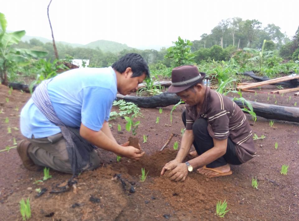 DCx founder Dane SO kneeling with an indigenous elder, preparing soil for rice and millet planting in a recently-cleared swidden plot